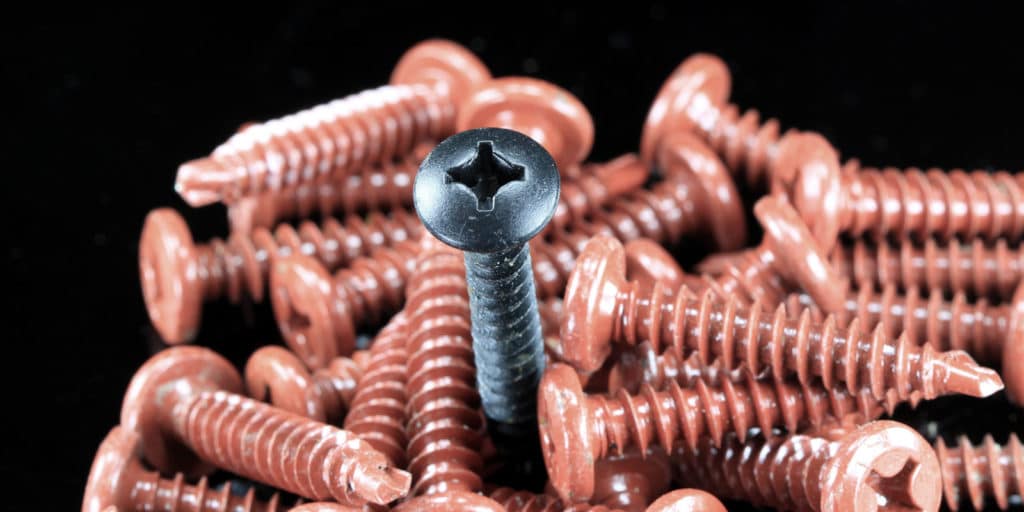 Silver screw in a field of rusty screws