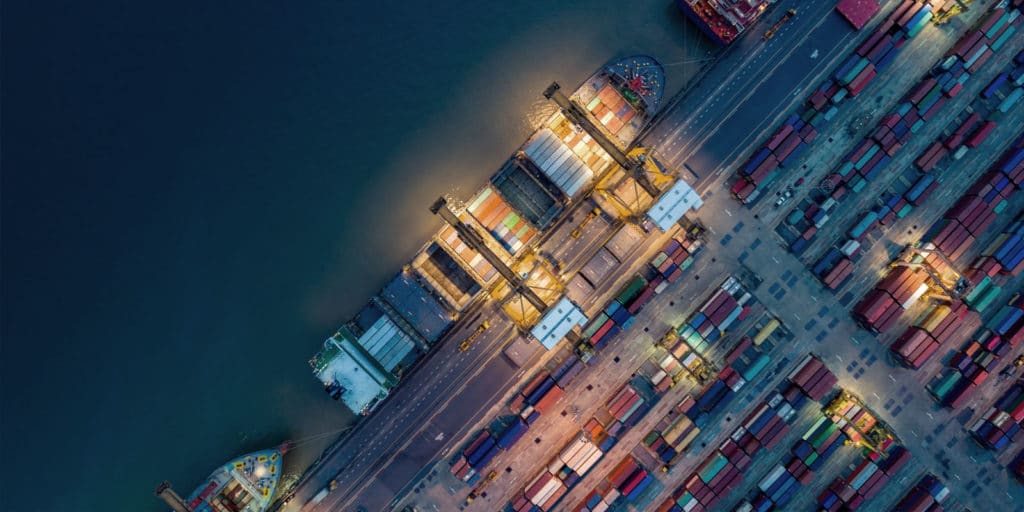 cargo ship docked at shipping yards with lots of shipping containers on the dock and the ship