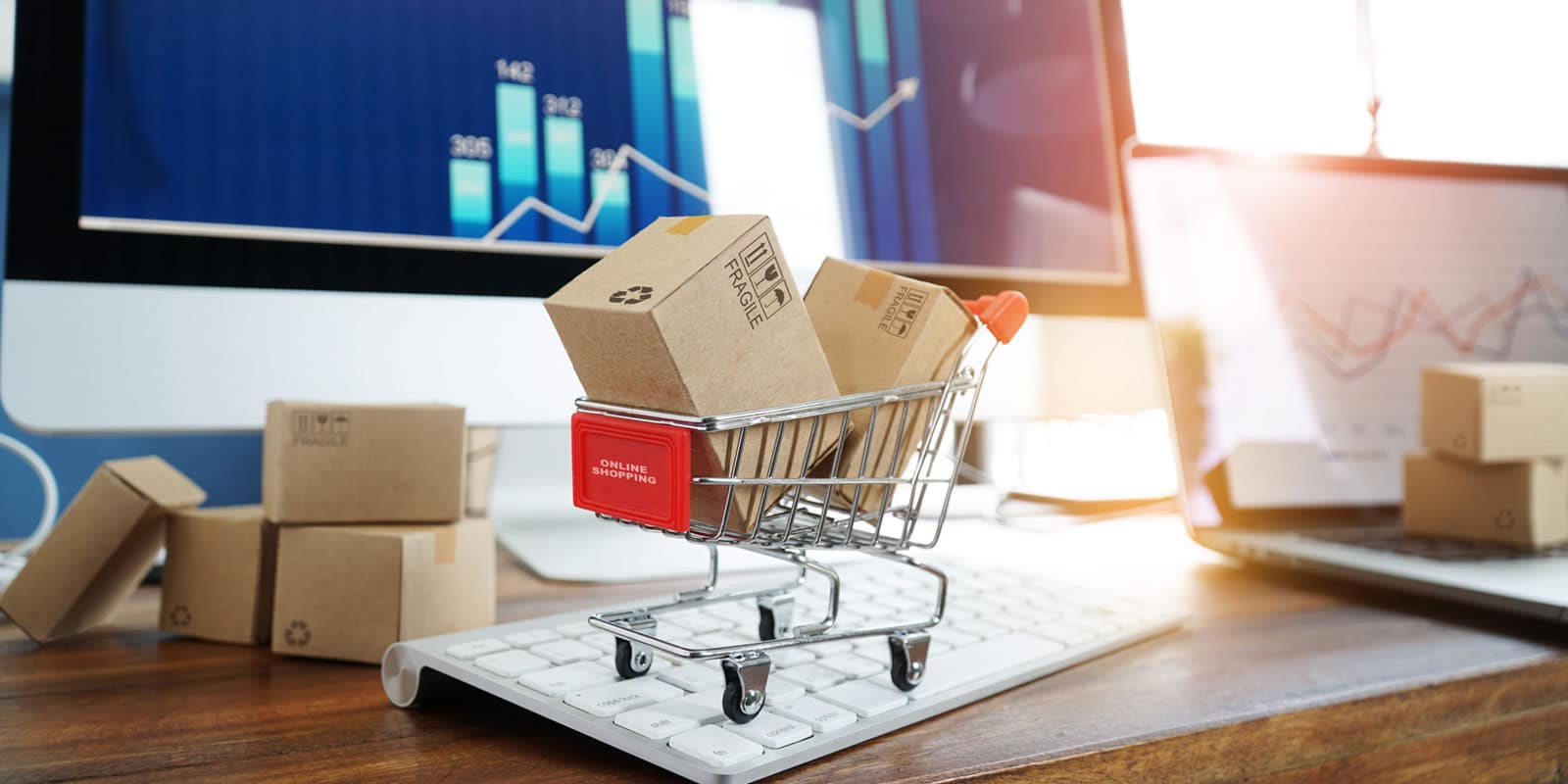 shopping cart on top of computer keyboard full of boxes