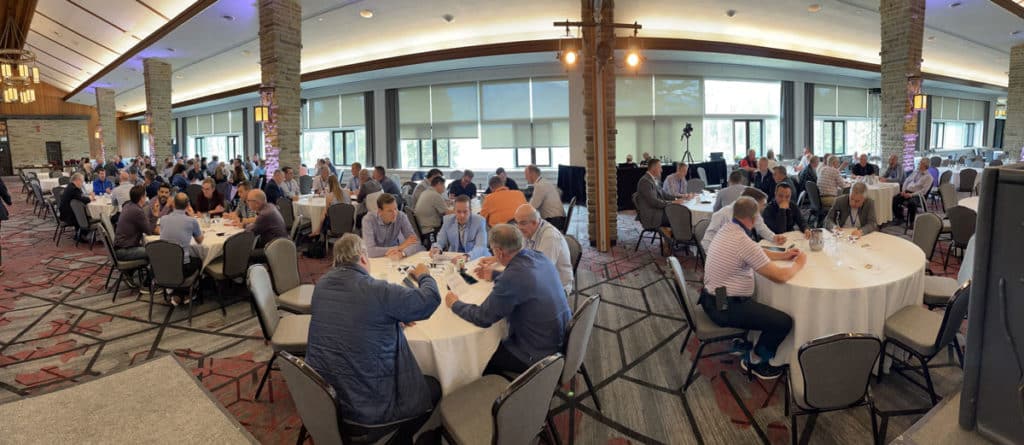 people sitting around circle shaped tables in a large hall
